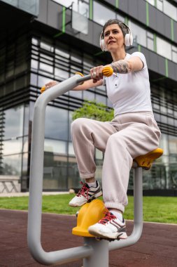 Günümüzde, spor salonunda bisiklet eğitmeni simülatöründe kısa saç eğitimi alan, modern, olgun, beyaz bir kadın spor salonu sağlıklı yaşam tarzı konseptini taklit ediyor.