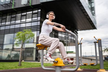 Günümüzde, spor salonunda bisiklet eğitmeni simülatöründe kısa saç eğitimi alan, modern, olgun, beyaz bir kadın spor salonu sağlıklı yaşam tarzı konseptini taklit ediyor.