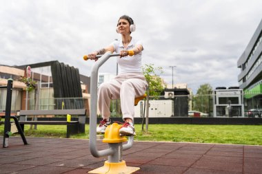Günümüzde, spor salonunda bisiklet eğitmeni simülatöründe kısa saç eğitimi alan, modern, olgun, beyaz bir kadın spor salonu sağlıklı yaşam tarzı konseptini taklit ediyor.