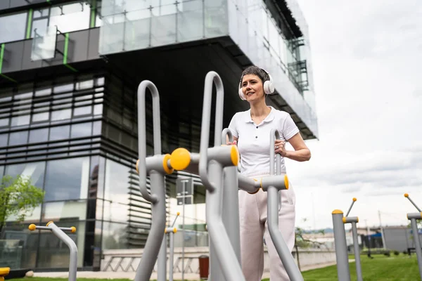 Gündüz bina önünde kısa saç eğitimi alan modern, olgun bir kadın spor salonunda eliptik eğitim makinesi simülatöründe sağlıklı yaşam tarzı konsepti sunuyor.