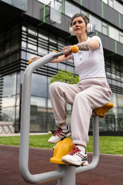 Günümüzde, spor salonunda bisiklet eğitmeni simülatöründe kısa saç eğitimi alan, modern, olgun, beyaz bir kadın spor salonu sağlıklı yaşam tarzı konseptini taklit ediyor.