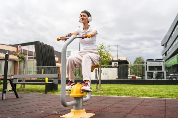 Günümüzde, spor salonunda bisiklet eğitmeni simülatöründe kısa saç eğitimi alan, modern, olgun, beyaz bir kadın spor salonu sağlıklı yaşam tarzı konseptini taklit ediyor.
