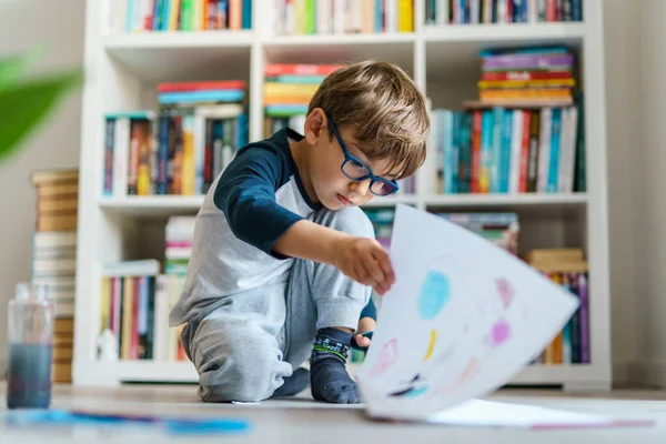 Evinde yerde oynayan dört yaşındaki beyaz bir çocuk hakkında ön görüş - suluboya resim yaparken boya kullanan küçük bir çocuk sanatsal beceriler geliştiriyor, eğlence ve yaratıcı eğitim geliştiriyor.