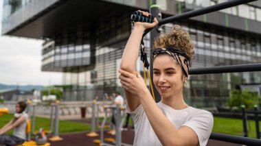 Genç bir kadın, kauçuk elastik direnç bantlarıyla beyaz kadın eğitimi. Açık spor salonunun spor salonundaki tüpleri. Sağlıklı yaşam tarzı konsepti.