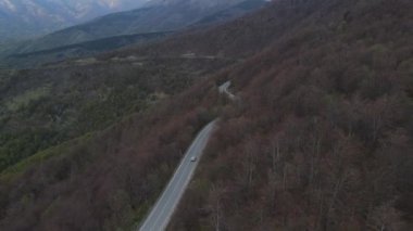 Top view on the road drone follow car while drive travel and tourism transportation concept in autumn or winter day trough the fields and trees on the old mountain stara planina  near Knjazevac Serbia