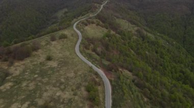 Top view on the road drone follow car while drive travel and tourism transportation concept in autumn or winter day trough the fields and trees on the old mountain stara planina  near Knjazevac Serbia