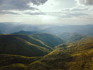 Günbatımının yüksek açılı hava görüntüsü güneş ışınları sonbahar veya kış günlerinde dağlık alanda ağaçlar ve ormanlar boyunca yolculuk ve tatil konsepti - Sırbistan 'daki Babin Zub Eski Dağı