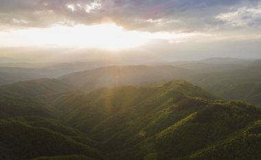 Günbatımının yüksek açılı hava görüntüsü güneş ışınları sonbahar veya kış günlerinde dağlık alanda ağaçlar ve ormanlar boyunca yolculuk ve tatil konsepti - Sırbistan 'daki Babin Zub Eski Dağı