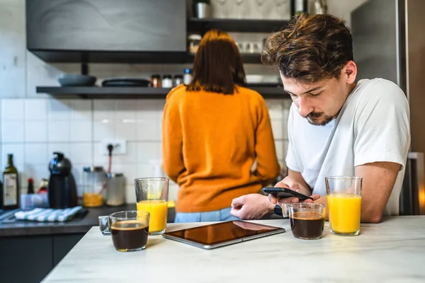 Hombre Utiliza Teléfono Móvil Cocina Mientras Novia Está Haciendo Desayuno — Foto de Stock