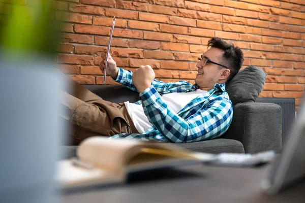 Genç bir erkek, evdeki ya da otel odasındaki kanepede oturup dijital tablet başarısı ve başarı konsepti fotokopi alanı kullanarak iş toplantısına hazırlanıyor.