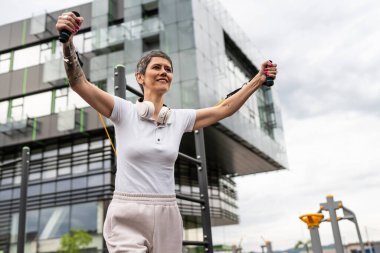 Bir kadın olgun ya da yaşlı, kauçuk elastik direnç bantlı beyaz kadın eğitimi. Açık spor salonunun spor salonundaki tüplerde. Sağlıklı yaşam tarzı konsepti.