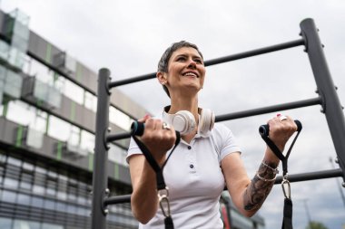 Bir kadın olgun ya da yaşlı, kauçuk elastik direnç bantlı beyaz kadın eğitimi. Açık spor salonunun spor salonundaki tüplerde. Sağlıklı yaşam tarzı konsepti.