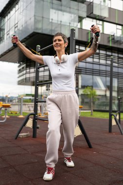 Bir kadın olgun ya da yaşlı, kauçuk elastik direnç bantlı beyaz kadın eğitimi. Açık spor salonunun spor salonundaki tüplerde. Sağlıklı yaşam tarzı konsepti.