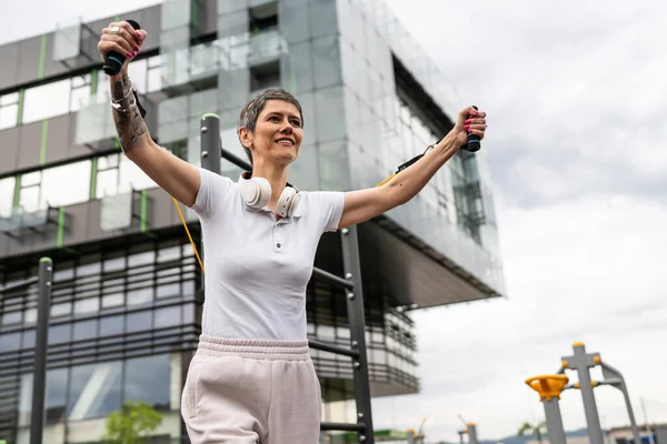 Bir kadın olgun ya da yaşlı, kauçuk elastik direnç bantlı beyaz kadın eğitimi. Açık spor salonunun spor salonundaki tüplerde. Sağlıklı yaşam tarzı konsepti.