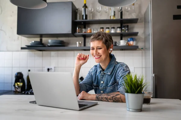 自宅のキッチンで彼女のラップトップコンピュータで働いている1人の女性成熟した白人女性リモートワーク朝のルーチン現実の人々コピースペース幸せな笑顔ビデオ会議コールを作る — ストック写真