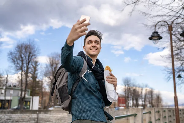 一个男人站在室外 在秋天的春天或冬天 拿着三明治游客穿着衬衫站在户外 在城市或城镇里用手机真实地复制太空快餐的概念 — 图库照片