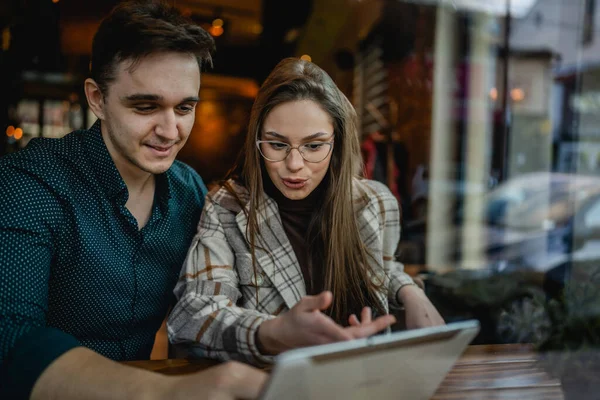 二人の若い大人のカップルの女性と男のボーイフレンドとガールフレンドや妻と夫がカフェの関係の概念に座ってオンライン検索やビデオ通話のためのデジタルタブレットを使用して実際の人々はスペースをコピー — ストック写真