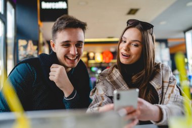 Kafkasyalı iki genç çift, kadın ve erkek arkadaş veya erkek arkadaş veya kız arkadaş selfie çekiyorlar ya da kafeteryada oturup eğlenirken ve romantizm yaparken görüntülü görüşme yapıyorlar.