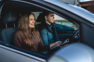 Erkek ve kadın genç çift ya da arkadaş erkek ve kadın sevgili mutlu bir gülümseme dijital tablet kullanarak yön haritası ararken araba içinde seyahat eden gerçek insanlar uzayı kopyalıyor.