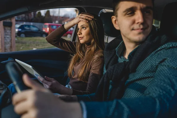 男と女若いですカップルや友人男性と女性のボーイフレンドとガールフレンド使用してデジタルタブレットのためのナビゲーション検索マップのための方向主張しながら 車の中で旅行実際の人々コピースペース — ストック写真