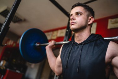 Spor salonundaki erkek sporcu, amatör ya da sporcu halterli ve omuzlarında ağırlık olan biri fotokopi alanı dayanıklılığını ve vücut geliştirme konseptini kapatıyor.
