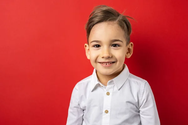 1人の男の子男の子5歳の赤い背景の壁の前に白いシャツを着てカメラを見て自信を持ってコピースペース腰まで幸せな笑顔 — ストック写真