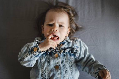 Beyaz bir kızın evde ceketle yattığı beyaz bir bebeğin portresi.