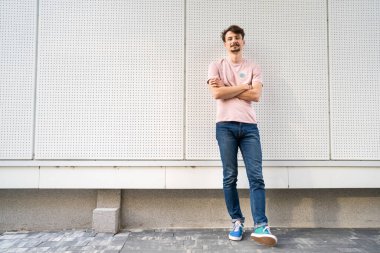 Kahverengi saçlı ve bıyıklı bir beyaz adam kameraya bakıyor modern mutlu yetişkin erkek gülümsüyor beyaz duvarın önünde kendinden emin bir portre tam boy fotokopi alanı