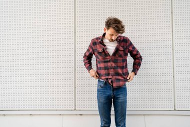 Kahverengi saçlı, bıyıklı, modern, mutlu, gülümseyen erkek portresi giyen beyaz duvar fotokopi alanının önünde genç bir beyaz adam.