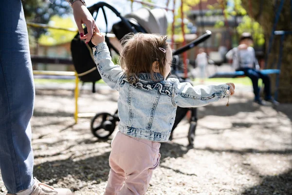 明るい春の日に歩くのを助けながら 彼女の母親が手を握って公園で一人の小さな白人の子供の女の子子供の頃の開発学習と家族の概念コピースペース — ストック写真
