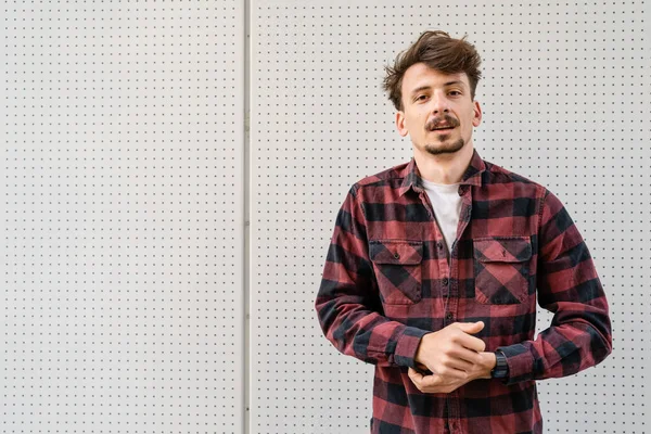 One young caucasian man with brown hair and mustaches wearing shirt looking to the camera modern happy adult male smile portrait in front of white wall copy space waist up