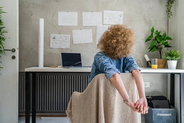 One woman adult mature caucasian female at her office desk sitting at work stretching arms Relaxation exercise Resting while taking a brake Workplace Concept copy space real people back view
