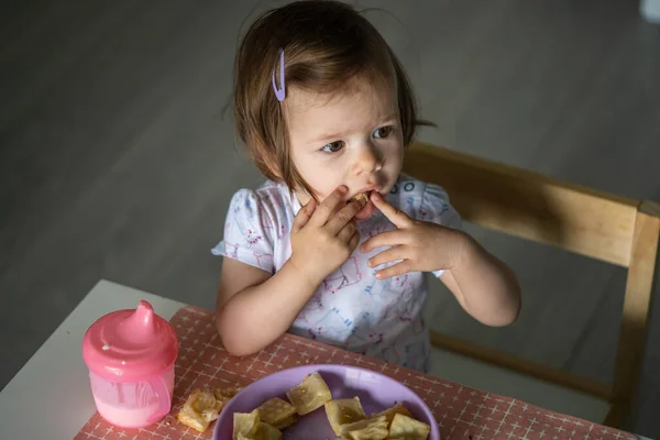 一人で家のテーブルに座っている一人の女の子の小さな白人の子供は 一日で一人でヨーグルトと朝食やランチの食事のペストリーを食べます現実の人々は 開発の概念コピースペースを成長 — ストック写真