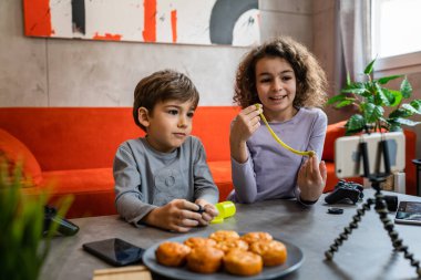 Erkek ve kız kardeş iki kardeş cep telefonuyla video blogu yapıyorlar evlerinden internet günlüğü için en sevdikleri oyuncak eleştirisi hakkında sosyal ağ kopyalama alanı için içerik oluştur ve paylaş