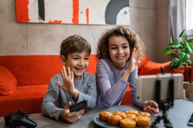 Erkek ve kız kardeş iki kardeş cep telefonuyla video blogu yapıyorlar evlerinden internet günlüğü için en sevdikleri oyuncak eleştirisi hakkında sosyal ağ kopyalama alanı için içerik oluştur ve paylaş