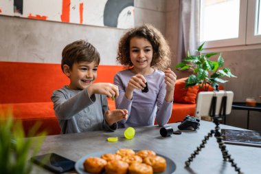 Erkek ve kız kardeş iki kardeş cep telefonuyla video blogu yapıyorlar evlerinden internet günlüğü için en sevdikleri oyuncak eleştirisi hakkında sosyal ağ kopyalama alanı için içerik oluştur ve paylaş