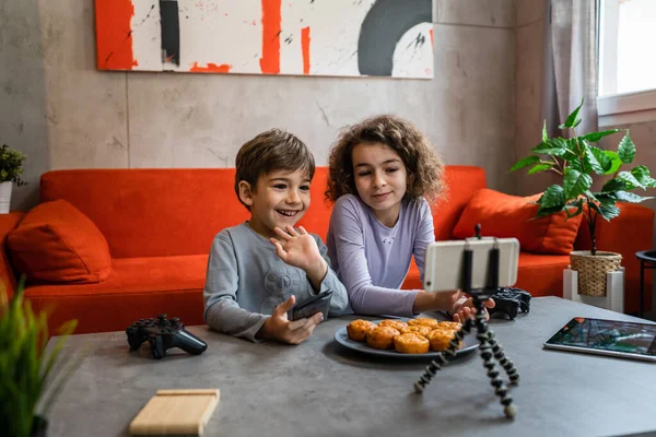 Erkek ve kız kardeş iki kardeş cep telefonuyla video blogu yapıyorlar evlerinden internet günlüğü için en sevdikleri oyuncak eleştirisi hakkında sosyal ağ kopyalama alanı için içerik oluştur ve paylaş