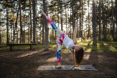 Kafkasyalı bir kadın ormanda yoga yapıyor ya da yalnız başına sağlıklı yaşam tarzı meditasyonu ve modern rahatlama germe konsepti fotokopi alanı ön görüşünü tam boy yapıyor.
