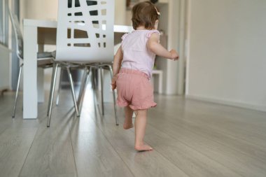 Oturma odasında koşan ve oynayan bir çocuk. Çocuk gelişimi ve öğrenme konsepti. Küçük beyaz bir kız.