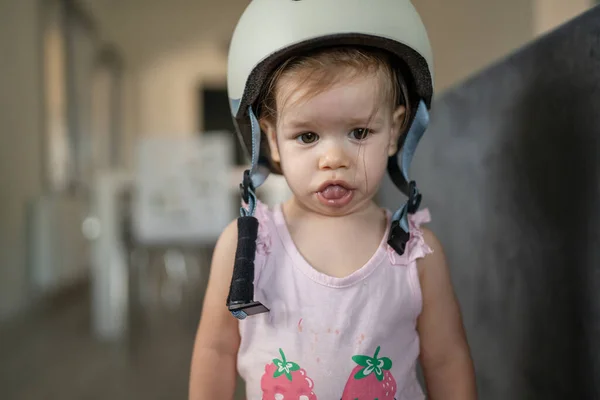 フロントビューポートレートの1人の女の子小さいCaucasian幼児赤ちゃん身に着けている保護ヘルメット頭の上に立っているか 部屋の中で家に歩いて新しいスキルを学ぶ早い開発コンセプト — ストック写真