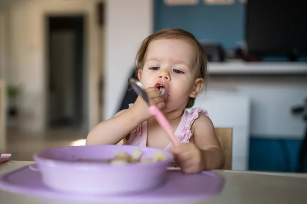 1人の子供小さな白人の幼児女性の赤ん坊はテーブルで一人で家で食べる現実の人々はスペースをコピーします — ストック写真