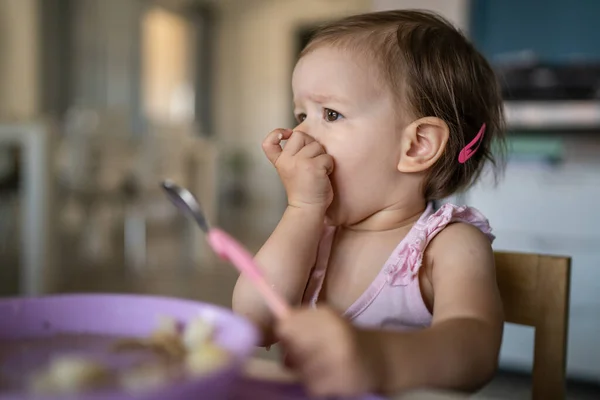 1人の子供小さな白人の幼児女性の赤ん坊はテーブルで一人で家で食べる現実の人々はスペースをコピーします — ストック写真