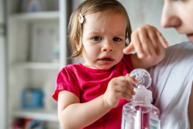One baby small caucasian child in hands of her mother holding a bottle of water opening or closing childhood and growing up family concept copy space