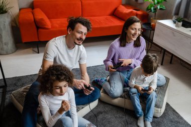 Bir grup Kafkasyalı aile adamı, kadın anne ve baba ellerinde çocuklarla evde oturmuş oyun konsolu ile oyun oynuyorlar. Oyun konsolu ya da kumanda çubuğu ya da gerçek insanlar konsepti kullanıyorlar.