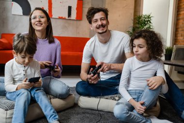 Bir grup Kafkasyalı aile adamı, kadın anne ve baba ellerinde çocuklarla evde oturmuş oyun konsolu ile oyun oynuyorlar. Oyun konsolu ya da kumanda çubuğu ya da gerçek insanlar konsepti kullanıyorlar.