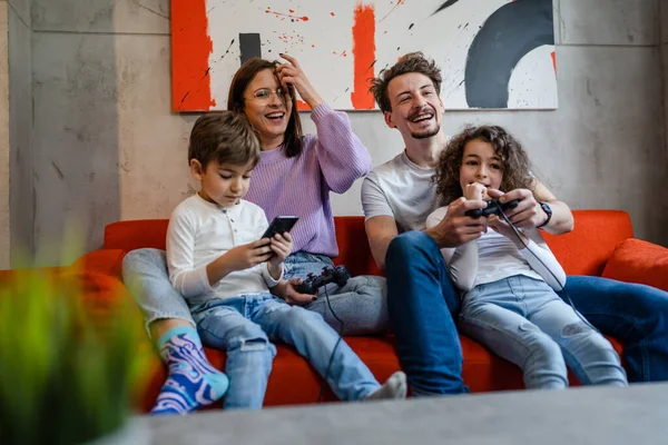 一群高加索人家庭男人和女人父母带着孩子坐在家里沙发上玩电子游戏 用的是控制杆或控制器真人的概念 — 图库照片