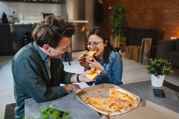 Young couple caucasian man and woman modern husband and wife eat pizza at home male and female friends having time together with food domestic life concept real people copy space selective focus