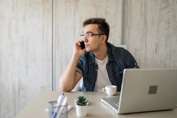 Kafkasyalı Bir Erkek Çalışma Masasındaki Ofiste Oturuyor Çalışırken Cep Telefonuyla — Stok fotoğraf