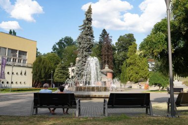 Vrnjacka Banja, Serbia - 08. 03. 2022: Fountain in a park spraying water with tourists in summertime