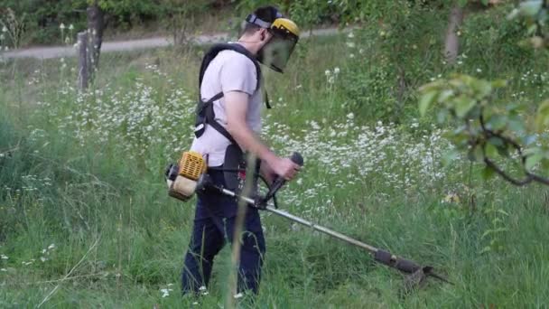 Νεαρός Καυκάσιος Κηπουρός Αγρότης Στέκεται Στο Χωράφι Χορτοκοπτικό String Βενζίνη — Αρχείο Βίντεο